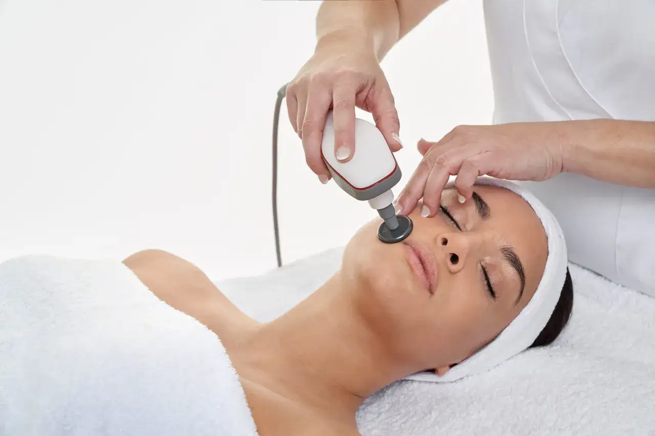 Una esteticista aplica un tratamiento facial con un dispositivo Indiba a una mujer.